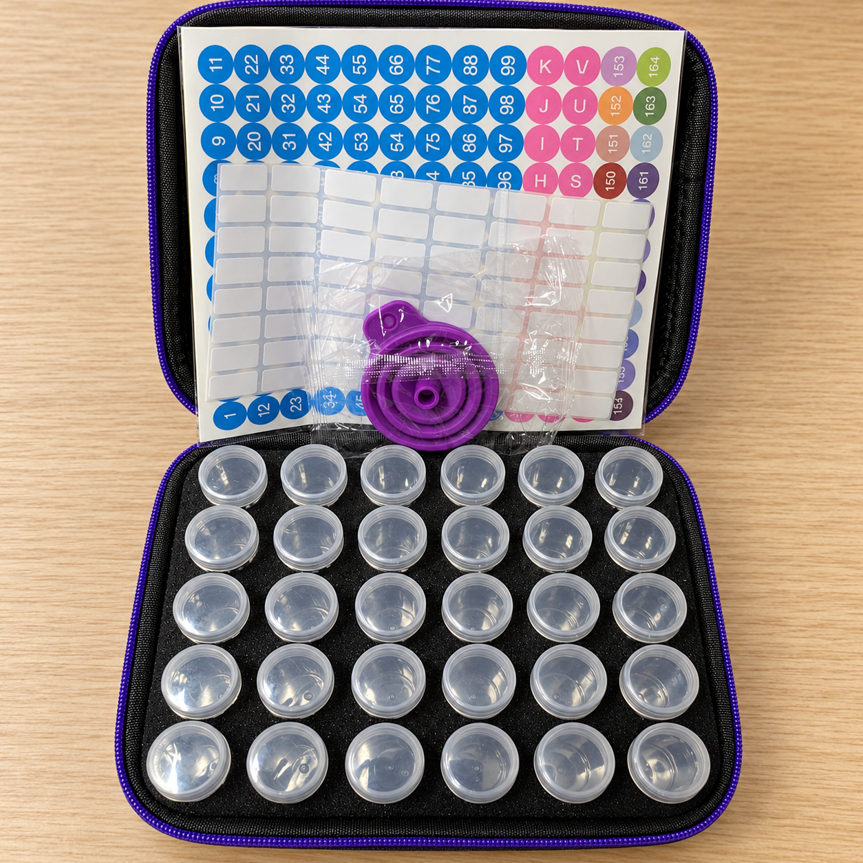 Geopende vosjeskoffer met 30 lege potjes, stickervellen en een paarse inklapbare trechter